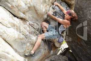 A challenging maneuver. A rock climber hanging onto a cliff face.