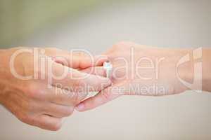 Finding the right one - Marriage and engagement. Cropped view of a mans hand sliding a wedding ring onto a womans ring finger.