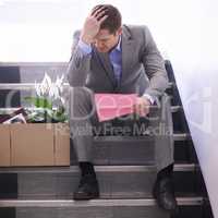 Hes been pink-slipped. Shot of a despondent businessman holding a pink slip terminating his employment.