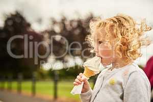 Fun and yum go well together. Shot of an adorable little girl eating an ice cream cone outdoors.