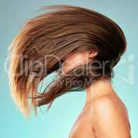 What a fabulous hair flip. Studio shot of an unrecognizable young woman posing against a blue background.