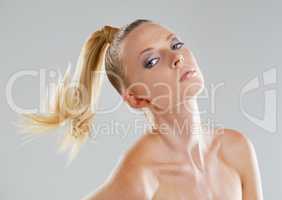 Giving you a striking stare. Portrait of a beautiful young woman with a ponytail against a gray background.