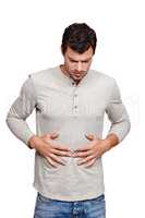 This stomach ache is so painful. A young man rubbing his stomach and grimacing while isolated on a white background.