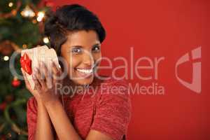 Its a Christmas eve tradition. Portrait of an attractive young woman holding her Christmas gift.