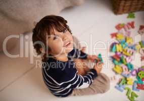 Imagination is the beginning of creation. Portrait of an adorable little boy playing with colorful toy letters.