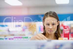 A young woman buying medicine in a pharmacy -The commercial designs displayed in this image represent a simulation of a real product and have been changed or altered enough by our team of retouching and design specialists so that they are free of any copy