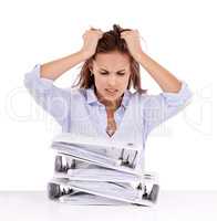 Aargh Ill never get through all this. Frustrated businesswoman with a stack of files in front of her - isolated on white.