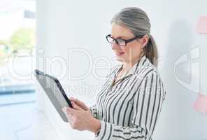 Completing tasks with ease and efficiency. Shot of a mature businesswoman using a digital tablet in an office.
