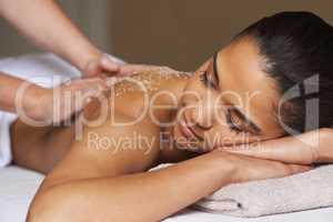 Massaging away all the worries and stress. Shot of a young woman enjoying a back massage at a spa.