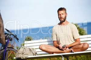 He cycled to his place of calm. Shot of a mature man listening to music while doing a relaxation exercise outdoors.