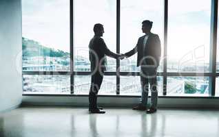 It all comes down to a handshake. Shot of two confident businessmen shaking hands in agreement while standing inside the office during the day.