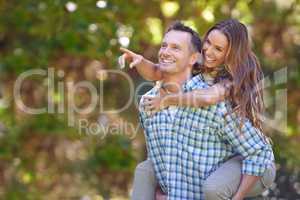 Look over there. A handsome man giving his wife a piggyback outdoors.