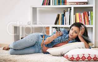 Relaxing and unwinding. Shot of a young woman watching television at home.