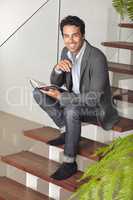 Checking his schedule. Portrait of a young businessman sitting on a staircase with his journal.