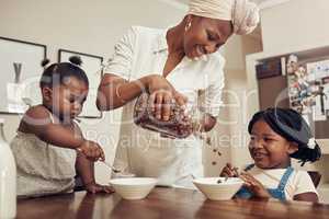 its time for breakfast. Cropped shot of a young mother preparing cereal for her two adorable young daughters at home.