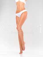 Perfectly toned and trim. Cropped view of a shapely female body in plain white underwear - isolated on white.