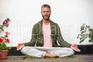 Mind over matter. Portrait of a handsome mature man doing yoga in an outside courtyard.