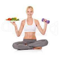Good food and exercise - The perfect combo. Portrait of a beautiful young woman holding a salad in one hand and a dumbbell in the other.