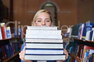 This is my study material for the semester. Portrait of a beautiful young student holding a large pile of textbooks.