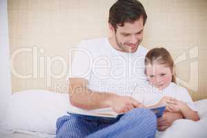 Looking at all the pictures. Shot of a devoted father reading his young daughter a bedtime story.