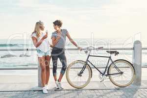 Were out for ice cream and fun. Shot of two friends eating ice cream while standing on the promenade with a bicycle.