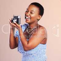 One capture, one hundred reasons, one thousand memories. Studio shot of a beautiful young woman using a camera against a oink background.