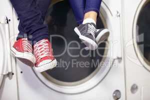 Theyre relaxed while doing laundry. Cropped image of a couples feet as they sit on a washing machine at the laundromat.