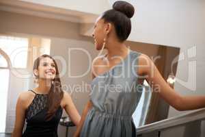 Ascending with grace. Shot of two beautiful women standing on an ornate staircase.