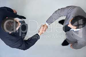Lets shake on it. High angle view of two businessmen shaking hands.