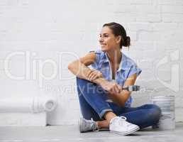 White really opens the room up. Shot of a woman holding a paintbrush while sitting on a floor.