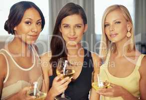 Shopping for clothing at an exclusive store. Portrait of three beautiful young women drinking white wine together.