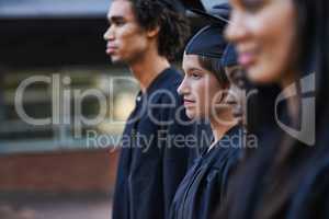 Facing their future as graduates. A group of solemn college graduates lined up at graduation.