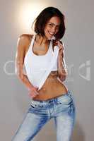 Fun and flirty. Cropped studio shot of an attractive young woman pulling at her tank top.
