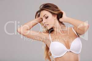 Voluptuous beauty. Studio shot of an attractive young woman posing in her bra against a gray background.