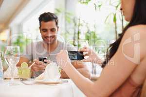 Romantic memories. A woman taking a picture while dining out with her partner at a restaurant.