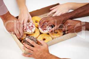 Take a bite of inspiration. A multitude of hands reaching to grab a doughnut from a box.