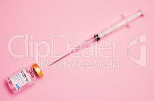 Extract the liquid to provide protection. Studio shot of a vaccine tube and syringe against a pink background.