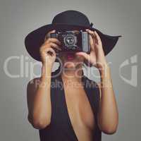 Strike a pose. Studio shot of a stylishly dressed young woman holding a vintage camera.