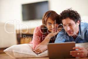 Time to unwind online. Shot of a husband and wife using a digital tablet together at home.