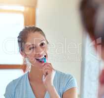 Oral health reflects your overall health. Cropped shot of a young woman brushing her teeth in a mirror.