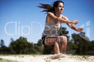 Going as far as she can. A young woman doing long jump.