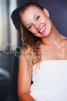 After bath - Cute woman wrapped in a towel and smiling. Portrait of a cute smiling woman wrapped in bath towel against a dark background.