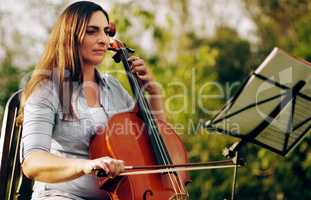 She takes every note seriously. Cropped shot of a beautiful woman playing a cello in the backyard.