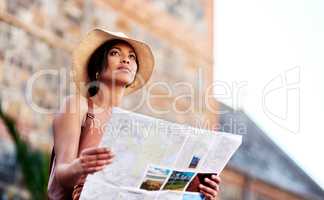 Theres plenty of sights to see. Shot of an attractive young woman holding a map while exploring in a foreign city.
