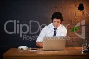 Another late night at the office. Shot of a businessman working at his laptop after hours.