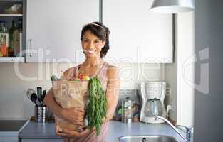 This is all I need for a healthy meal. Portrait of a young woman holding a paper bag of fresh produce.