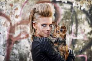 Urban dog. A young trendy woman holding a small dog in an urban setting.