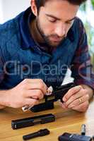 Regular maintenance is essential for every gun owner. A young man cleaning his gun.