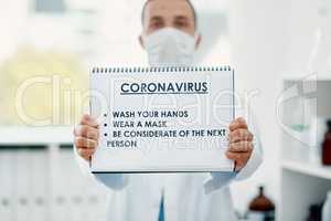 Do your bit to evade the virus. Shot of a scientist holding a sign with a list of COVID-19 prevention measures on it in a laboratory.