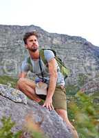 He knows where hes going. Shot of a handsome young man scaling a mountain.